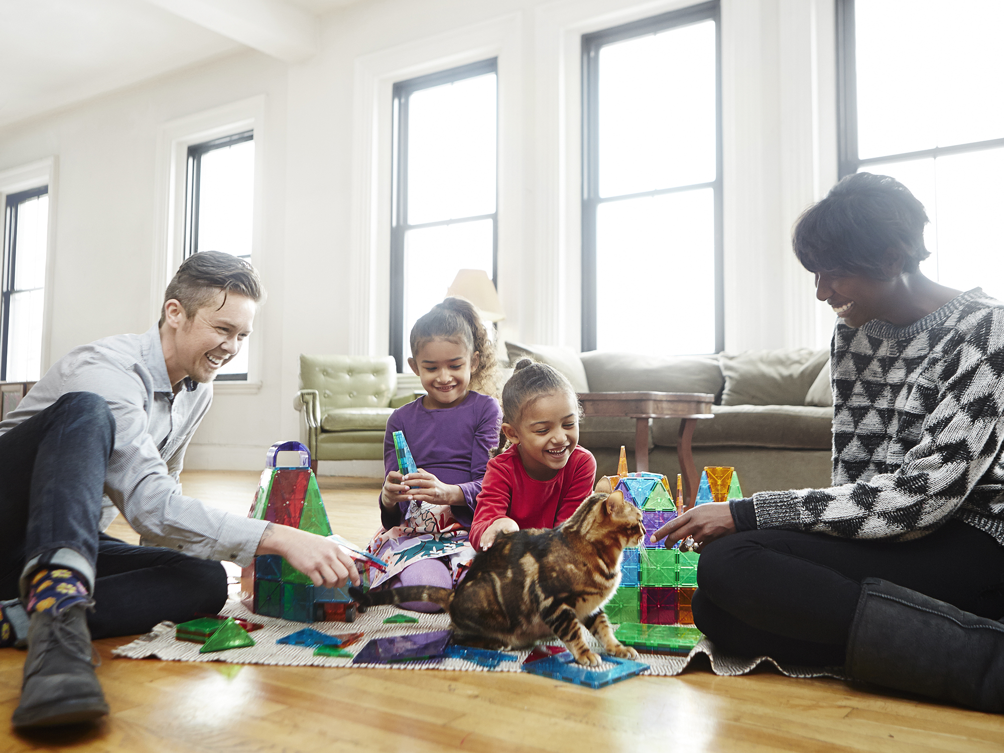 Transgender dad plays with daughters and partner in living room