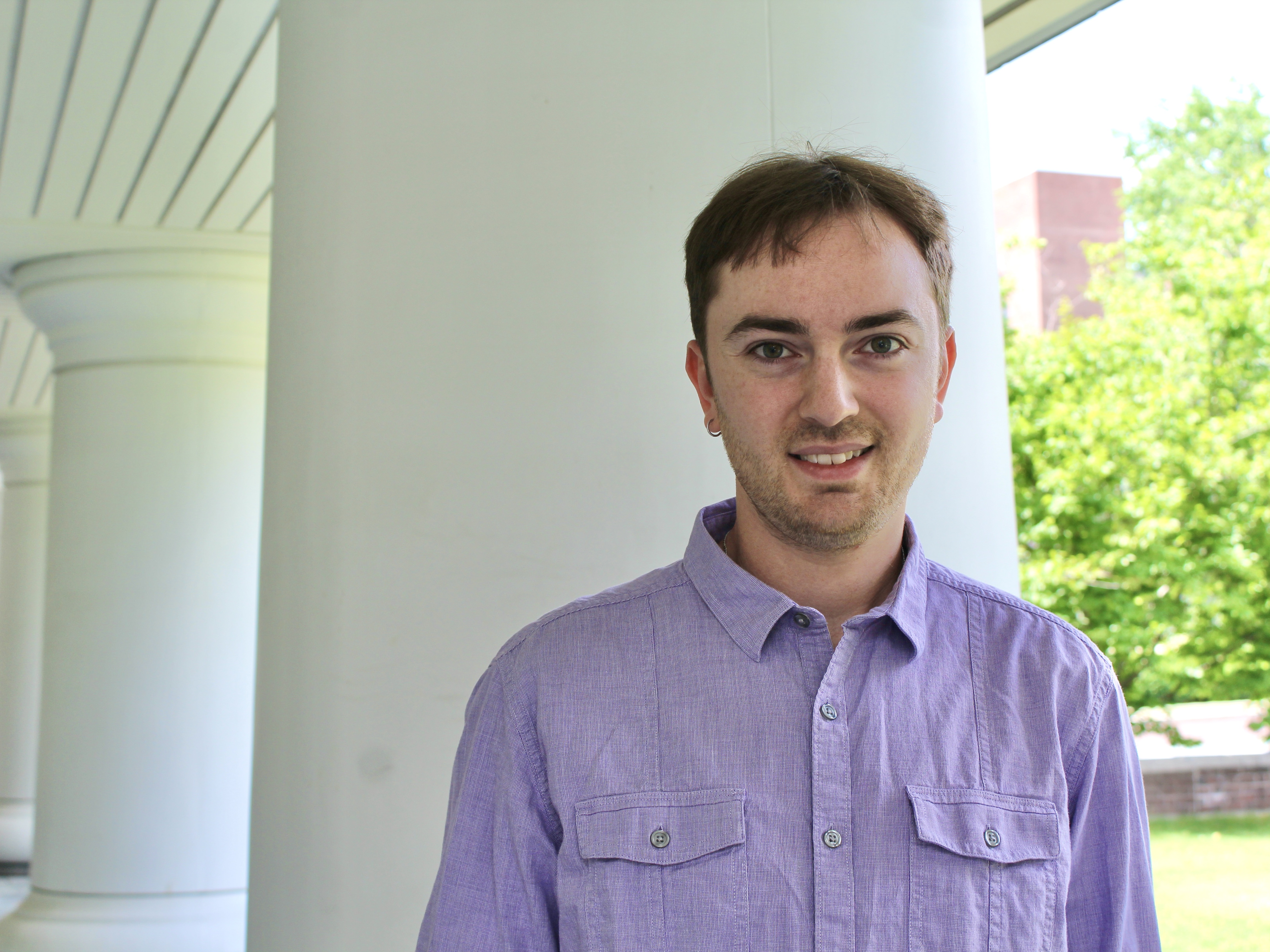 Kato Griffiths, the Liberal Arts college marshal for summer commencement, stands in front of the Hintz Family Alumni Center at Penn State University Park