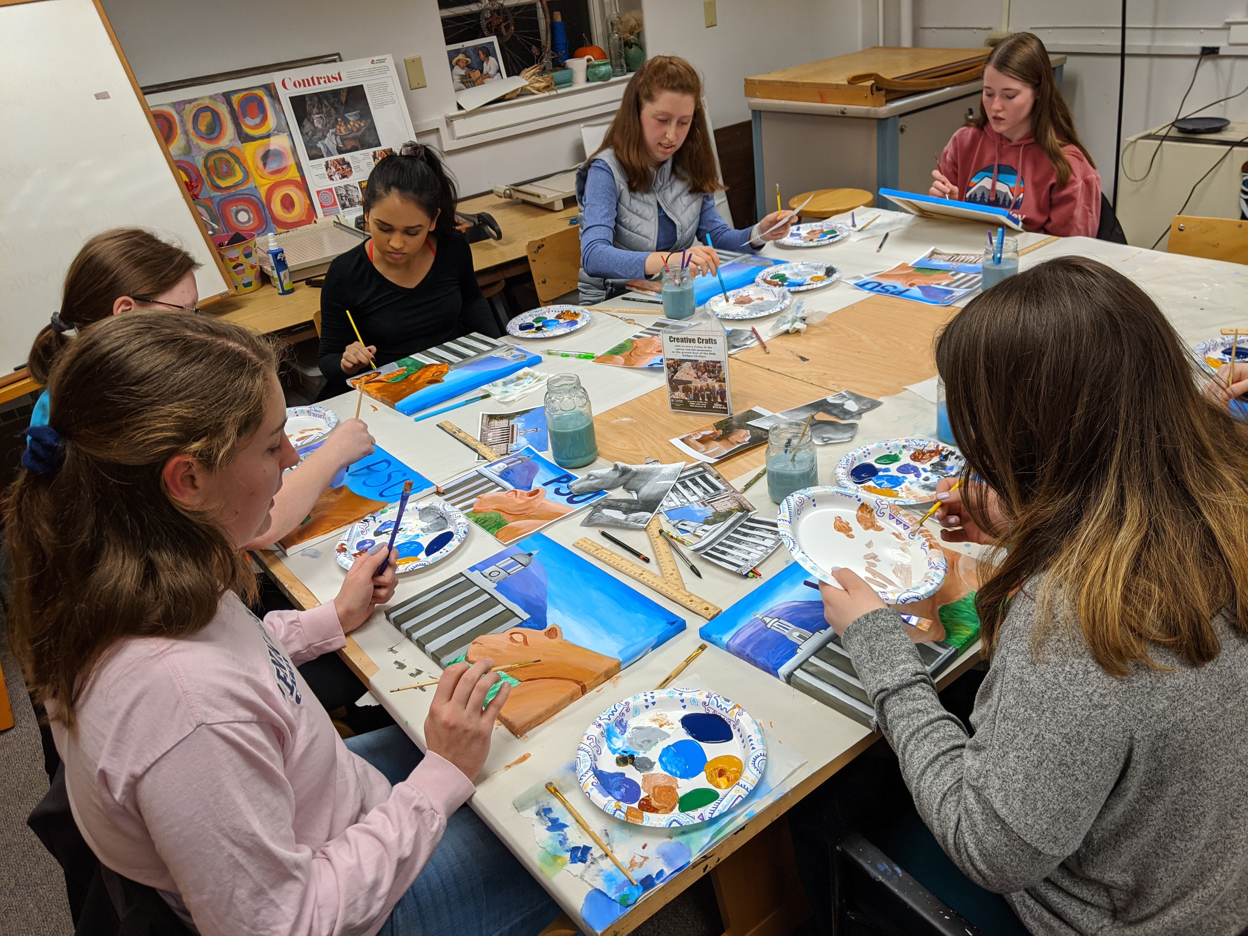 students sitting around a table painting