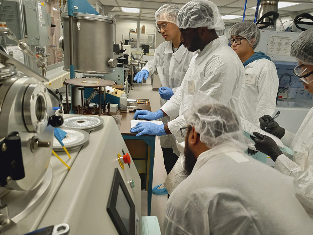 five people wearing safety wear in manufacturing laboratory