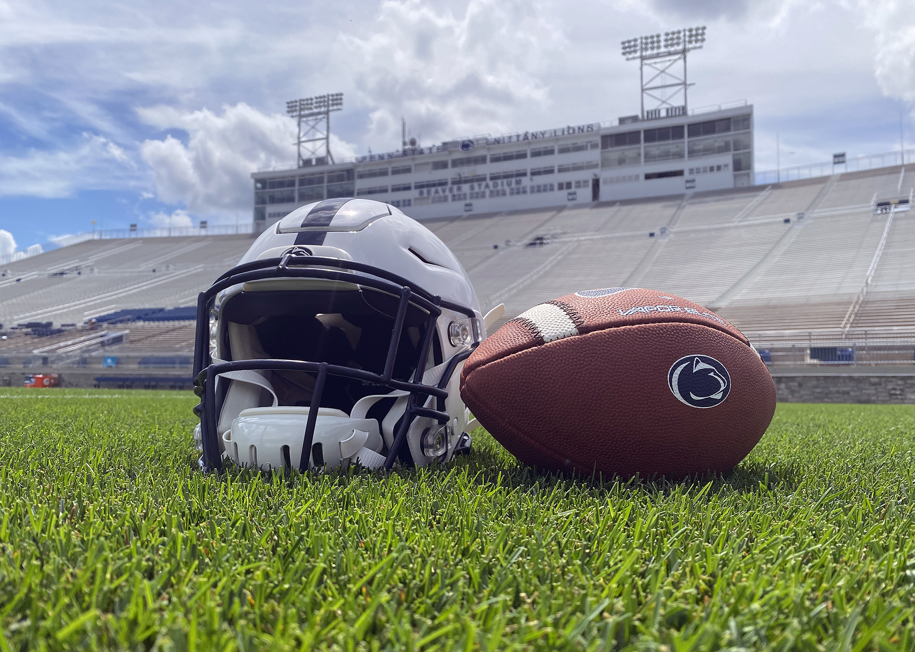 A football and helmet on the field at Beaver Stadium