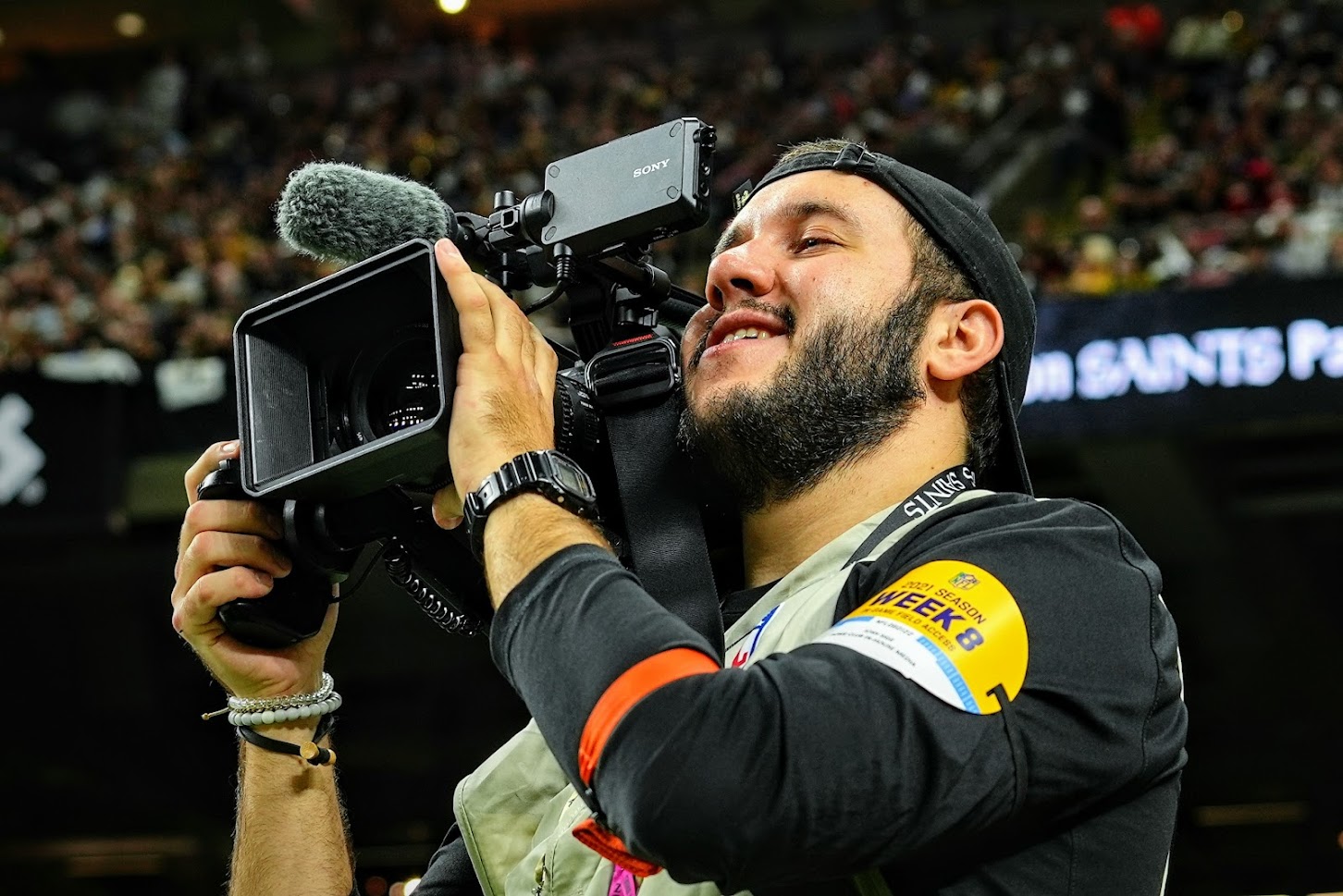 Josh Sige looks through a video camera on the sideline during an NFL game.