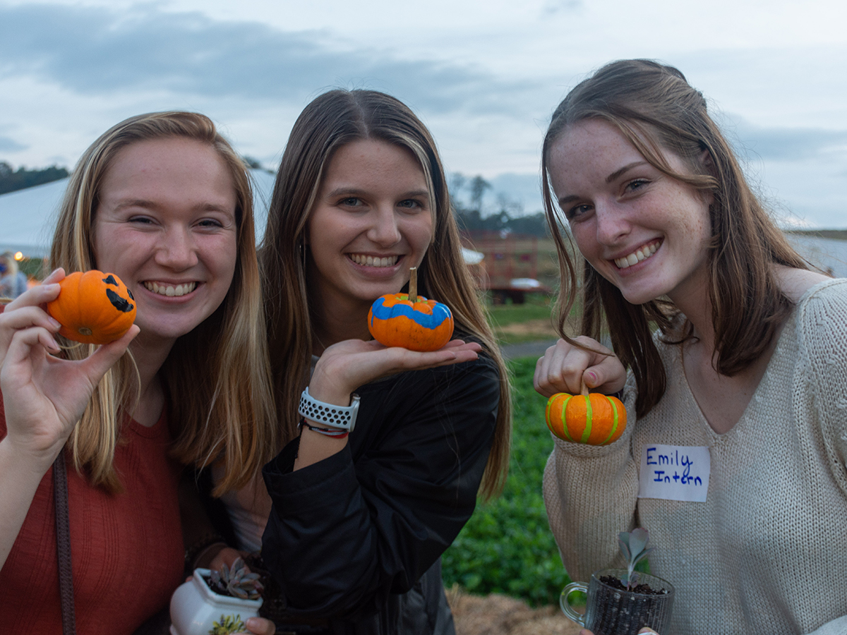 Three students holding painted pumpkins