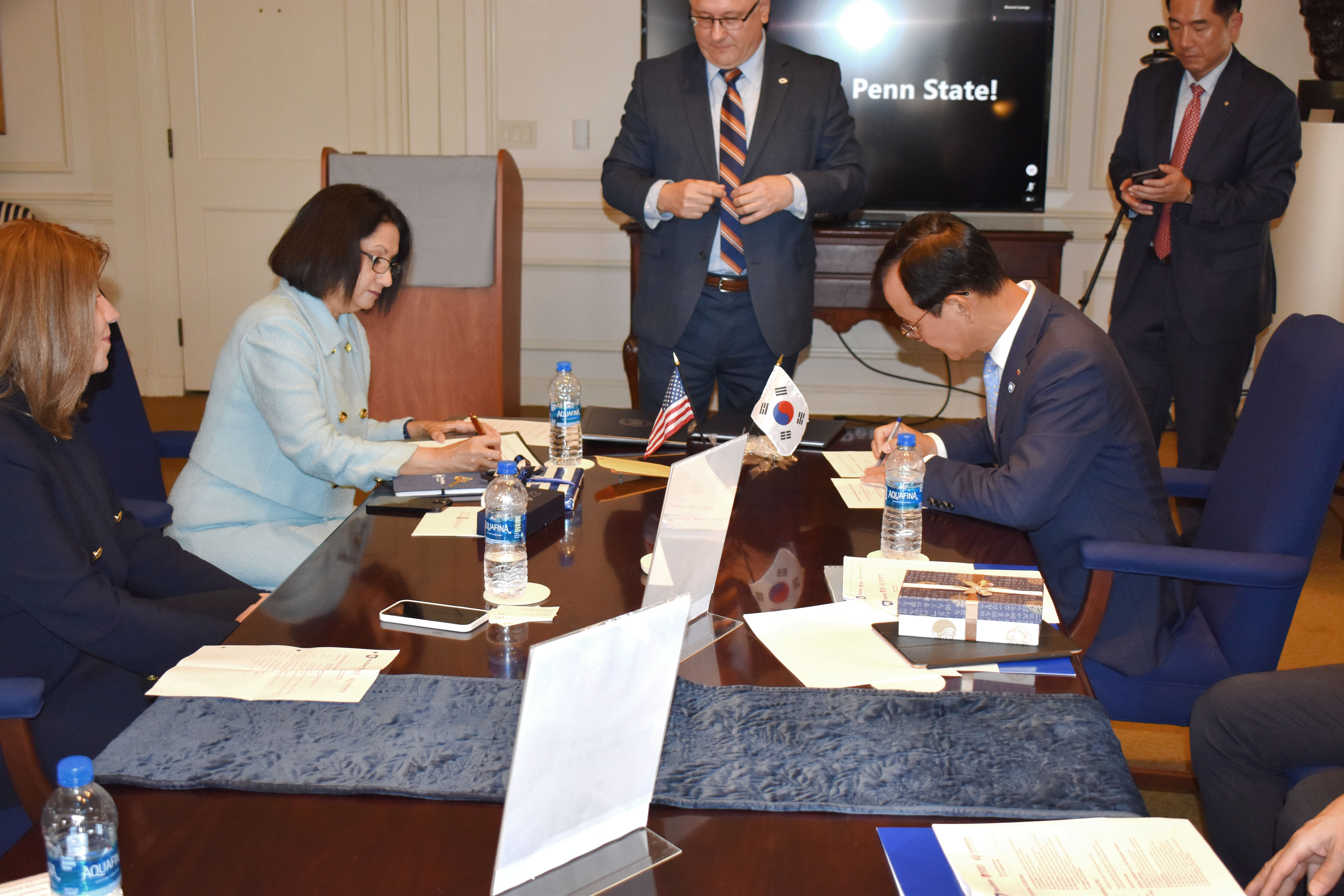 Two university presidents, one male and one female, signing an agreement