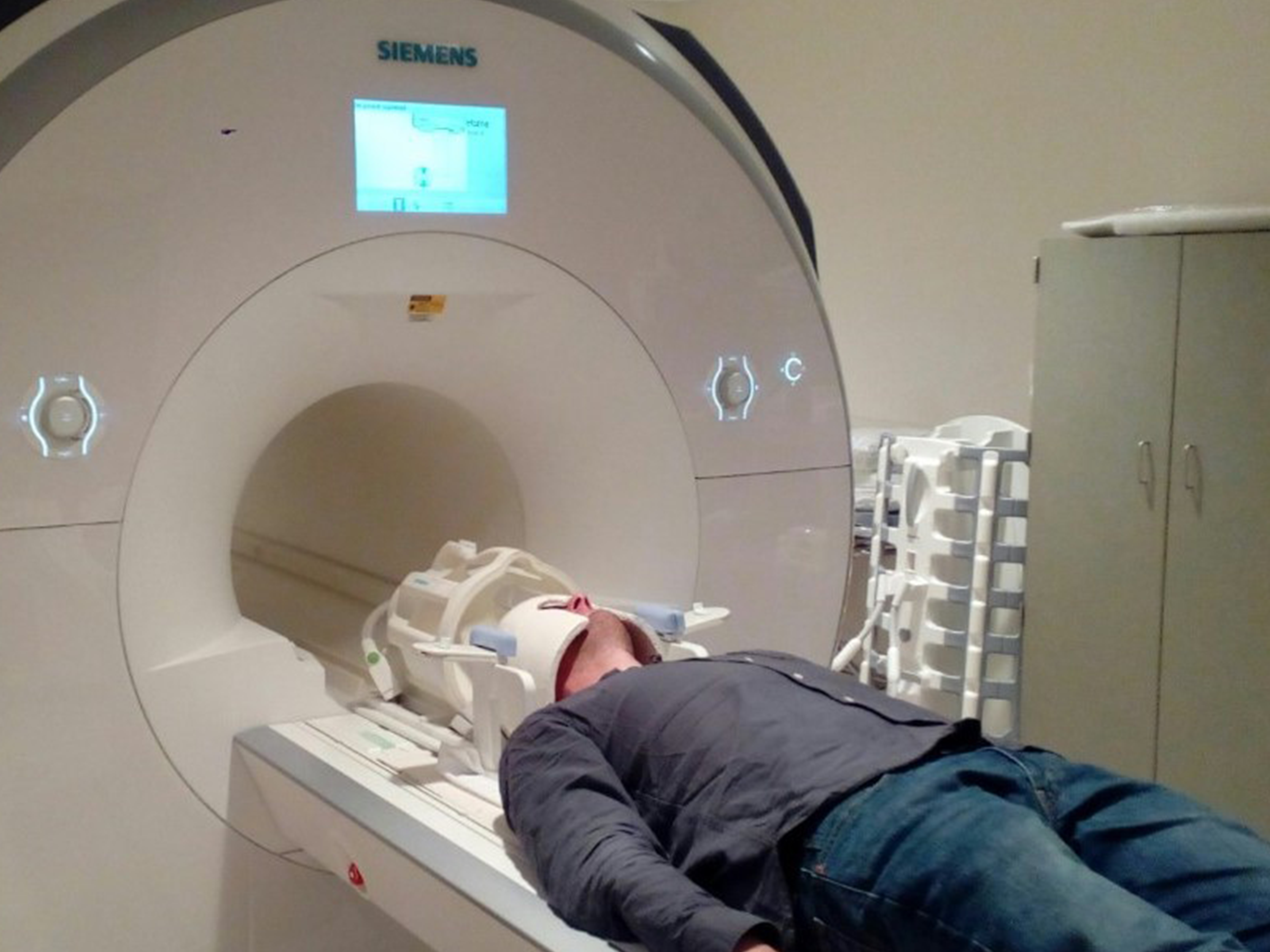 Man in ceramic helmet being loaded into MRI machine.