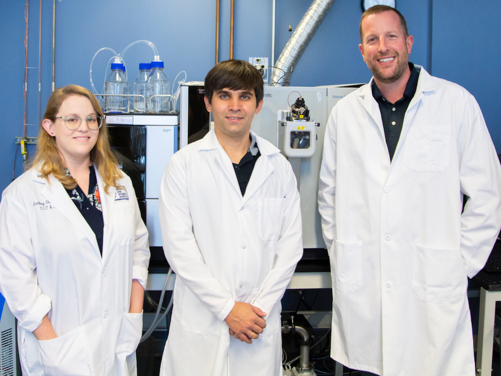 A group of researchers look at the camera, they are wearing lab coats.