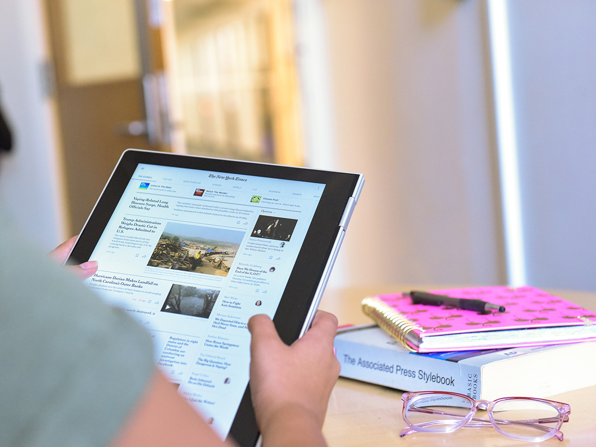 Student Reading a newspaper on a tablet