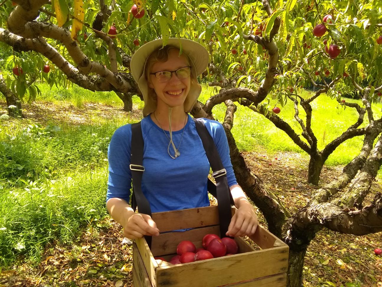 Sara Hricko holding a basket of apples and smiling