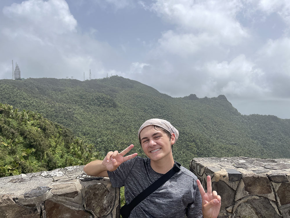 Caden Vitti poses in front of mountains at El Yunque, a national rainforest in Puerto Rico.