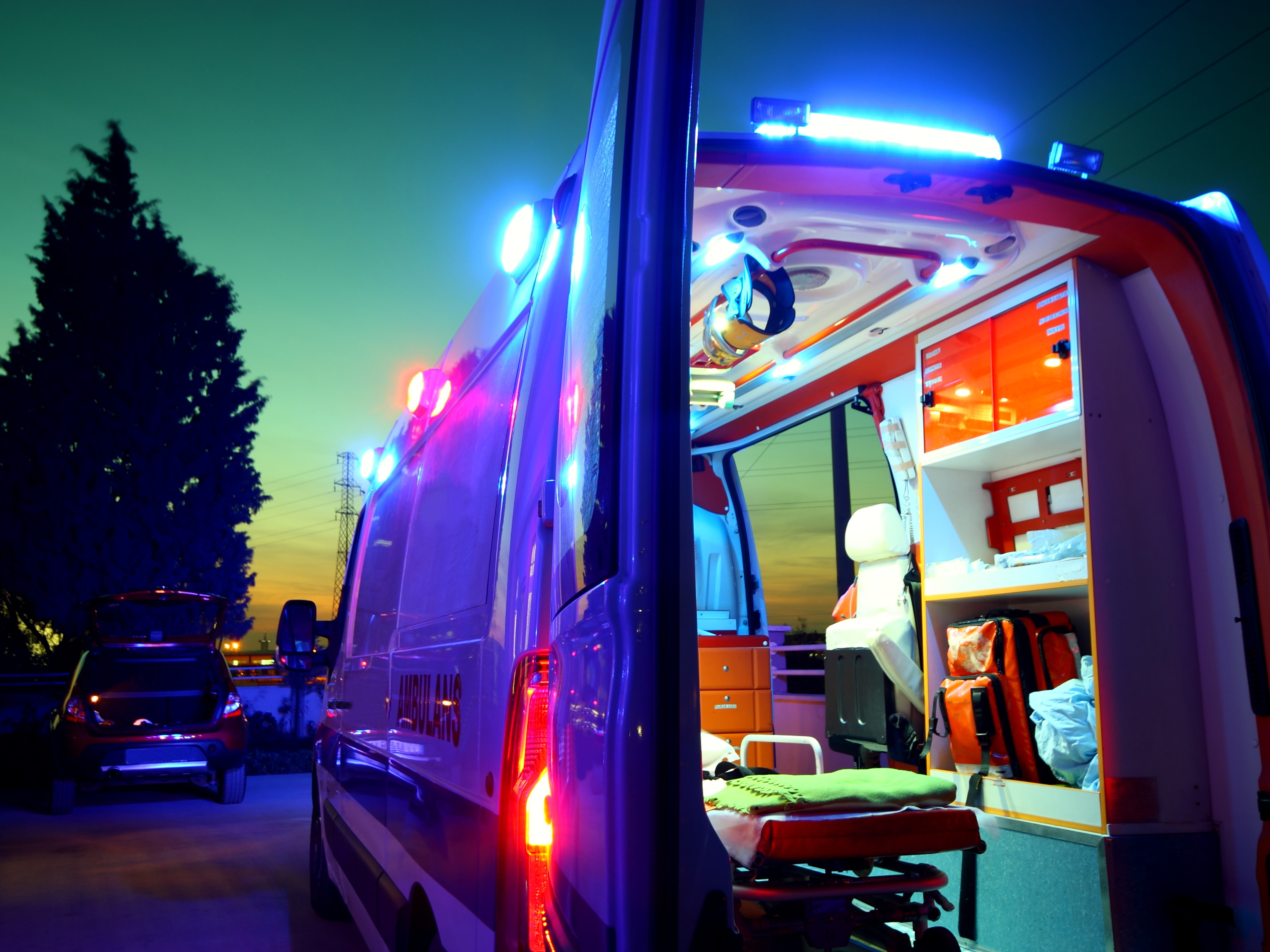 the brightly lit interior of an ambulance with its back doors open, at night