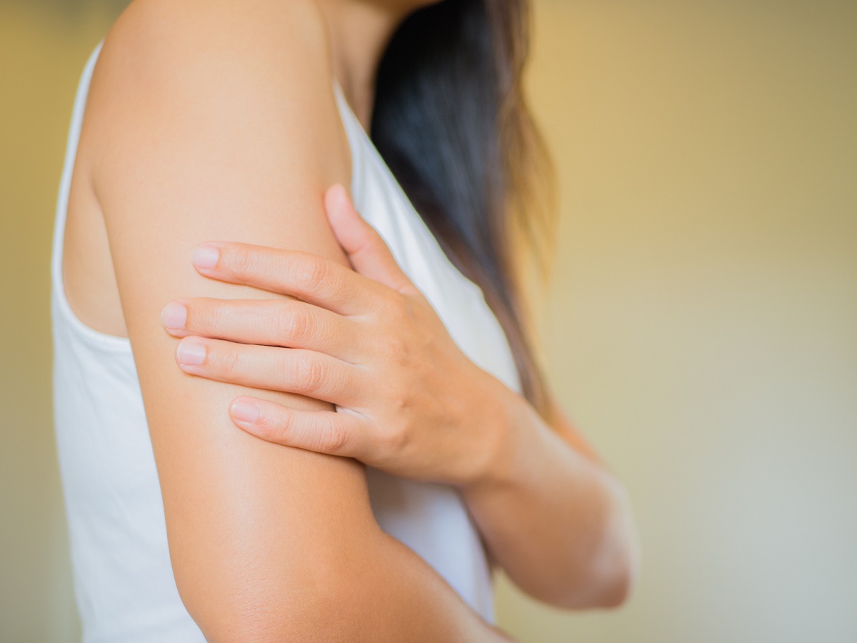 Close-up of a woman holding her arm.