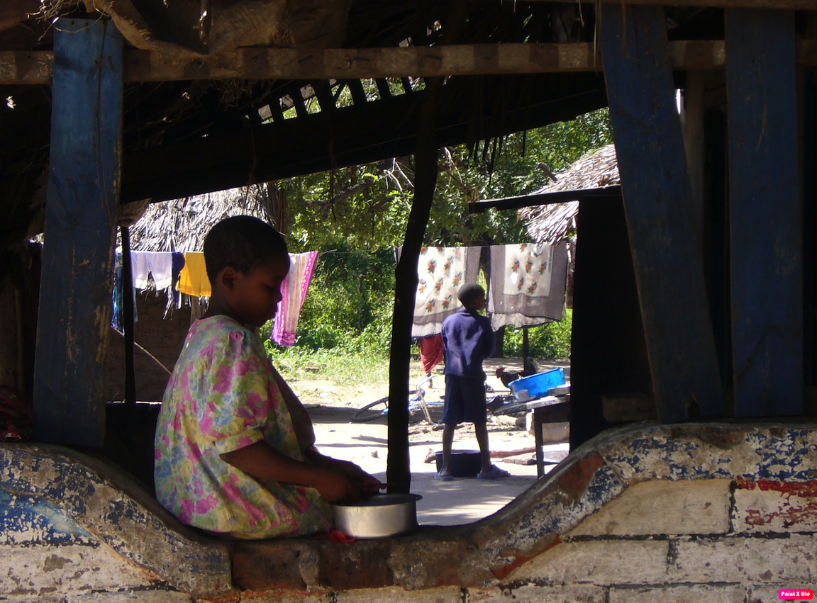 A child sitting on a low wall in Tanzania