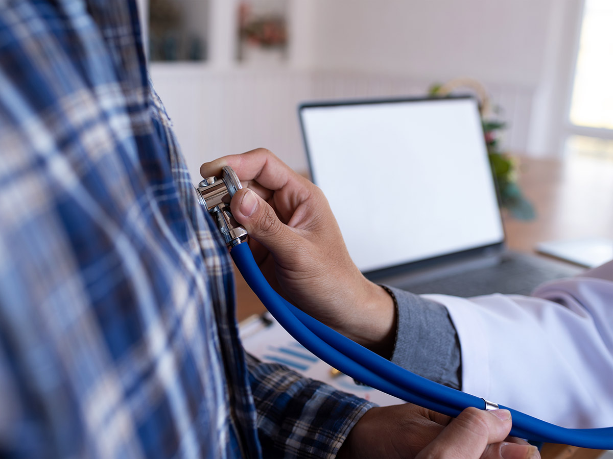 A doctor holds a stethoscope over a patient's chest. 