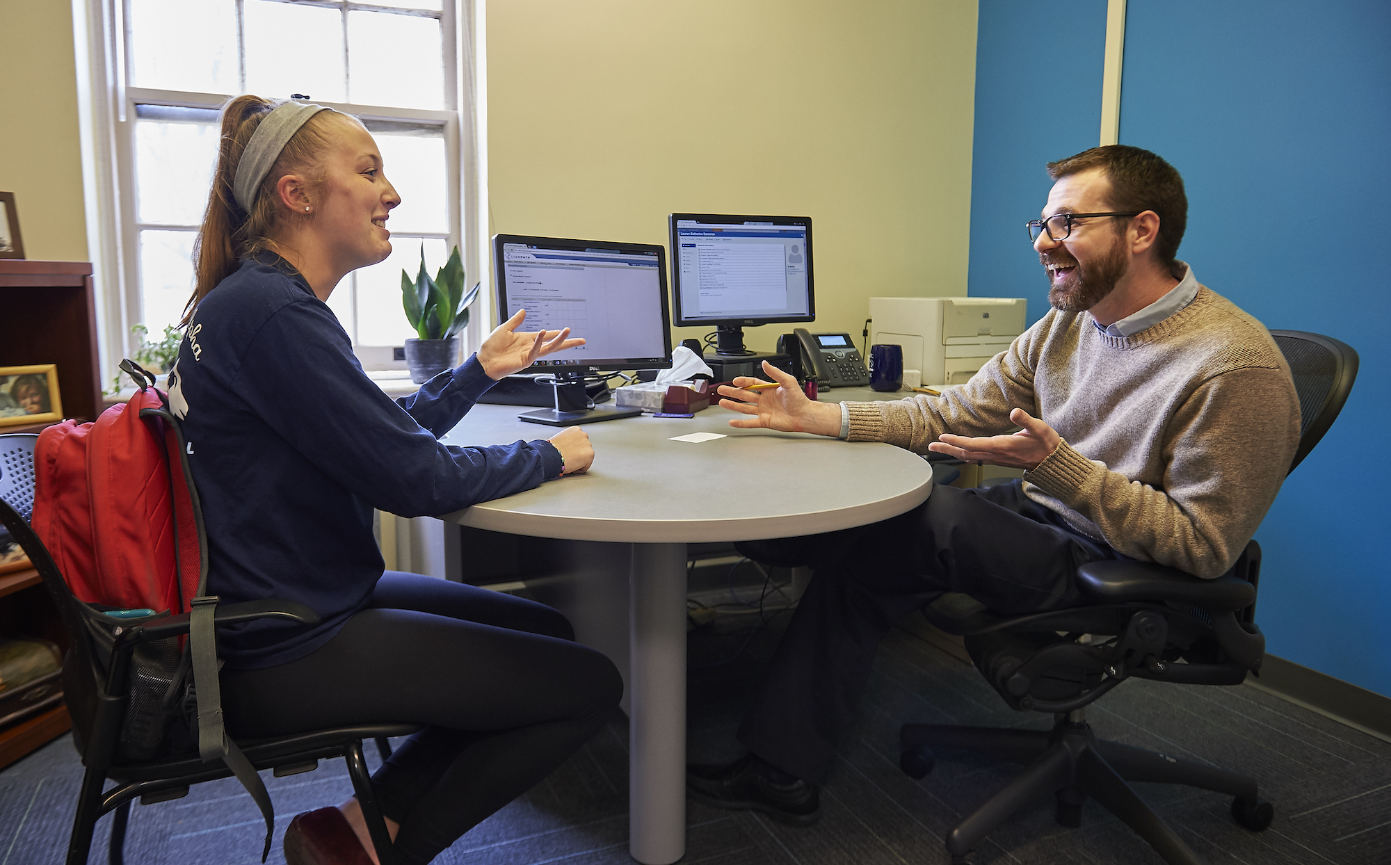 Student sitting across from academic adviser talking and smiling