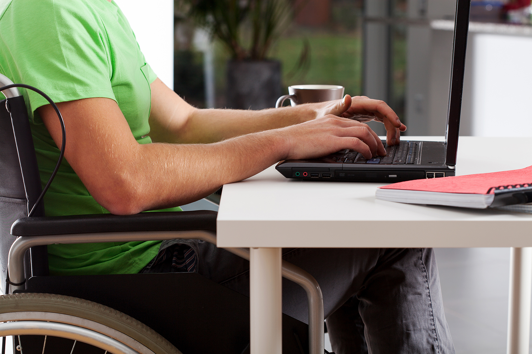 A man in a wheelchair uses a laptop