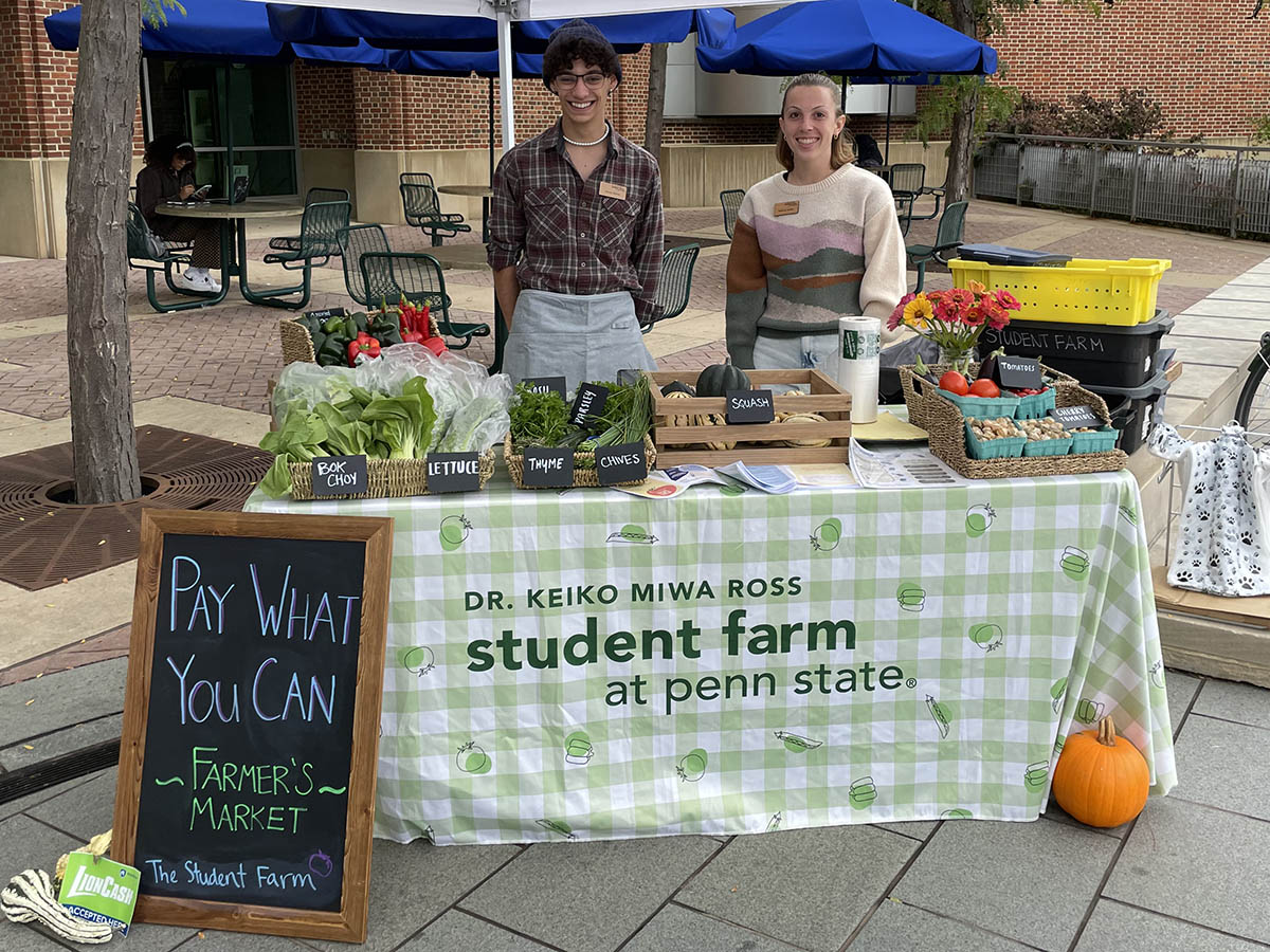 students standing behind a farm stand by the HUB