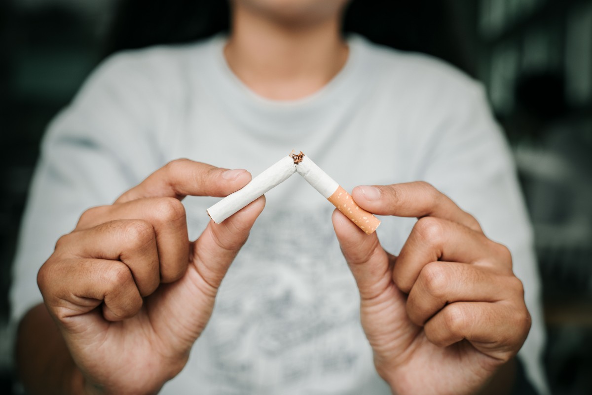 A person breaks a cigarette in half with their hands.