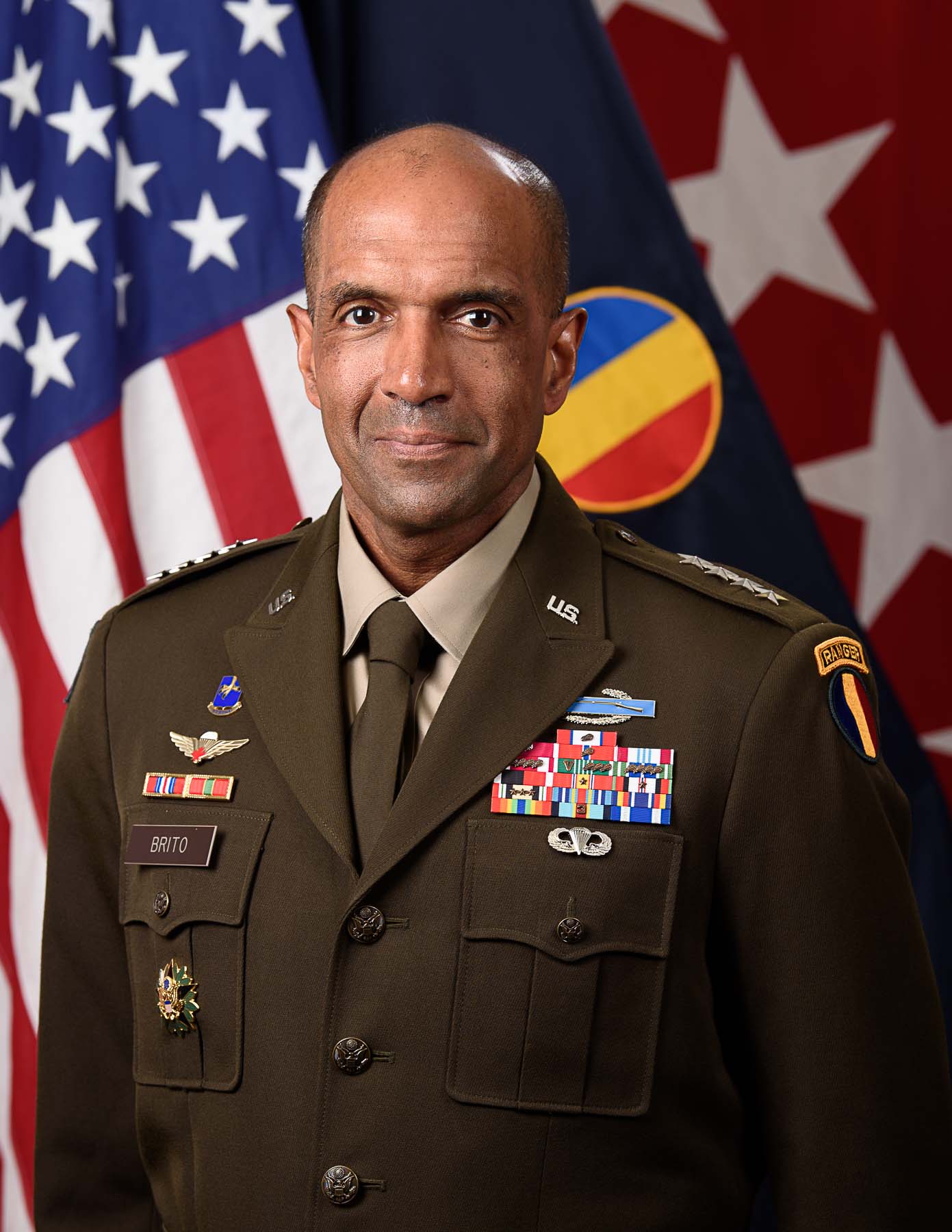 Official portrait of General Gary Brito in uniform in front of three different flags