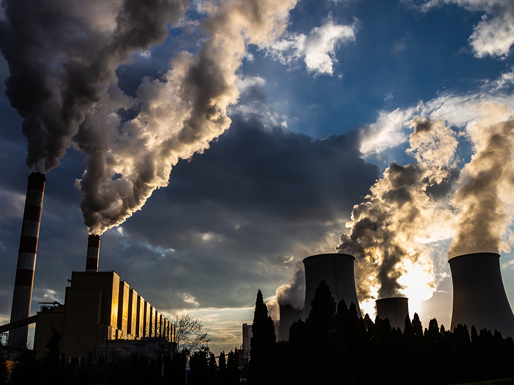 A power plant emitting smoke at sunset.