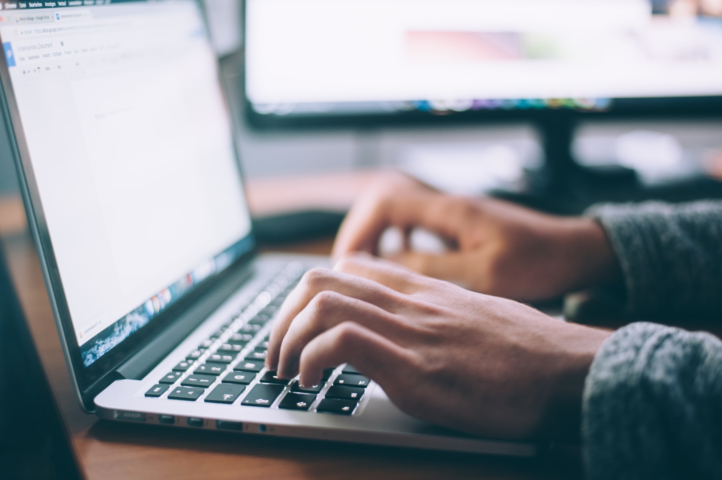 A person's hands typing on laptop computer