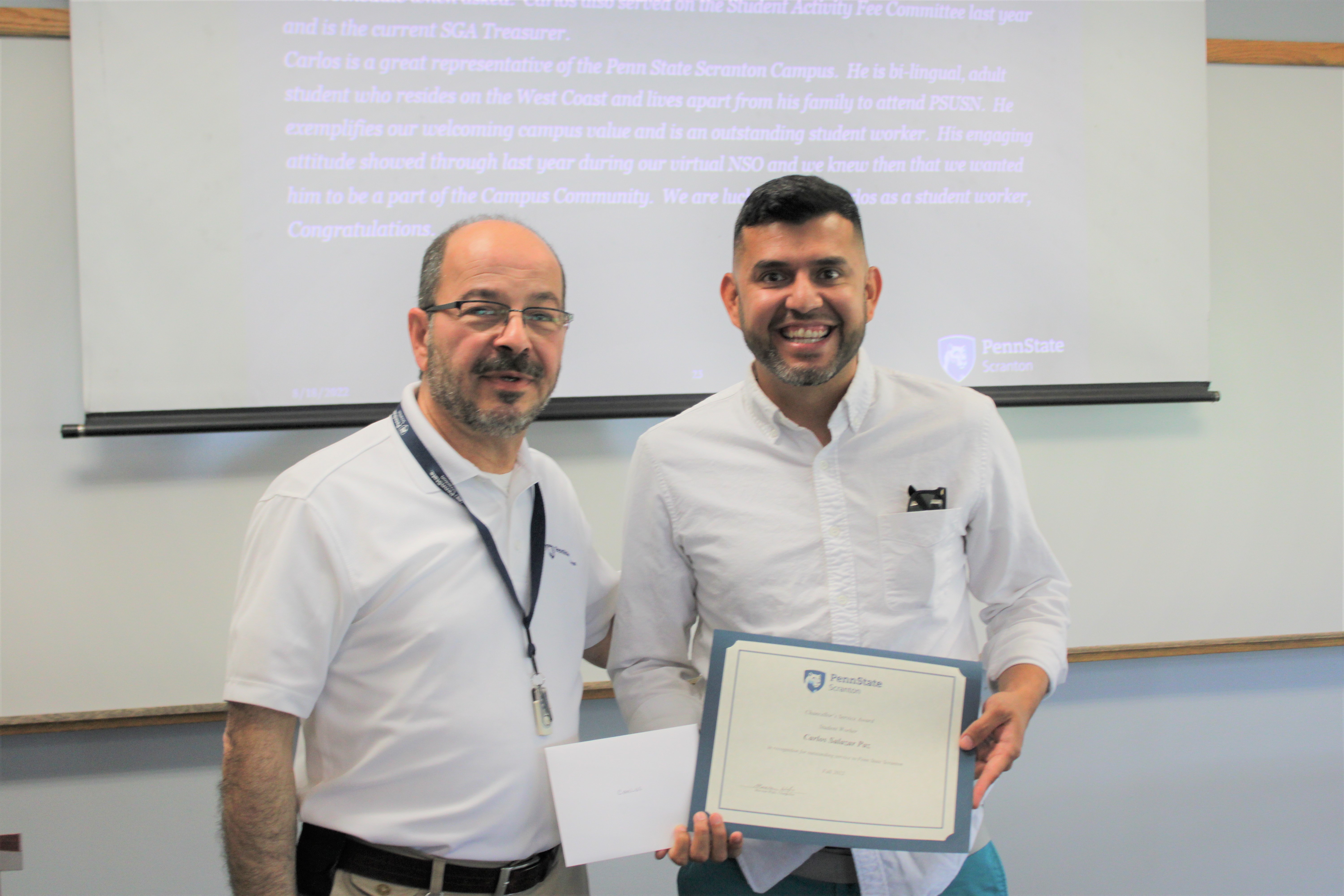 Chancellor Marwan Wafa, left, presents the Chancellor's Service Award certificate to Carlos Salazar Paz.