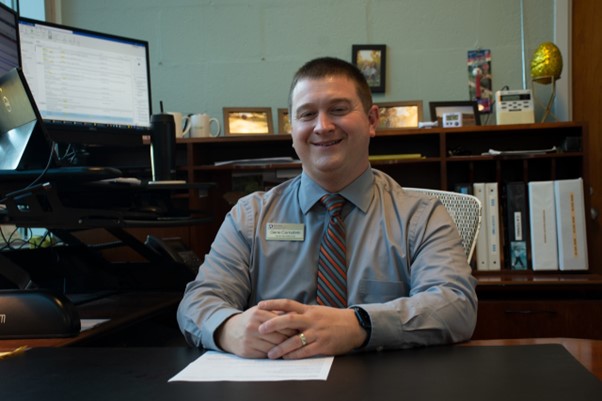 A man smiling behind a desk