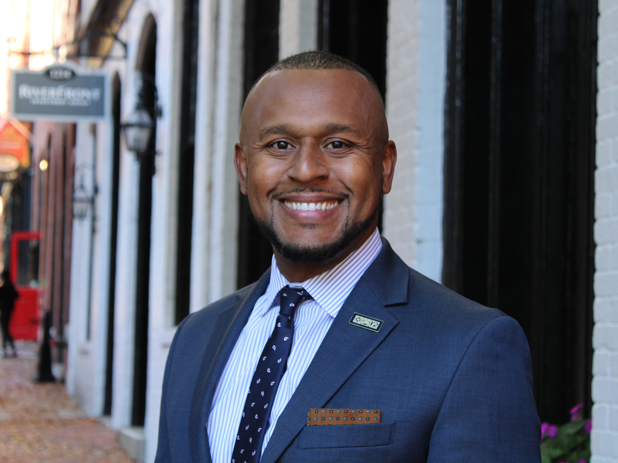 A headshot image of Larry Terry in a suit with buildings in the background