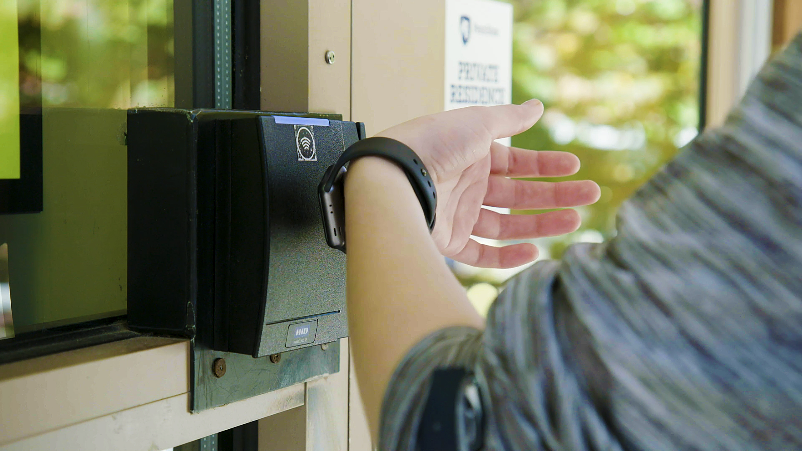 Student using Apple Watch to open door. 