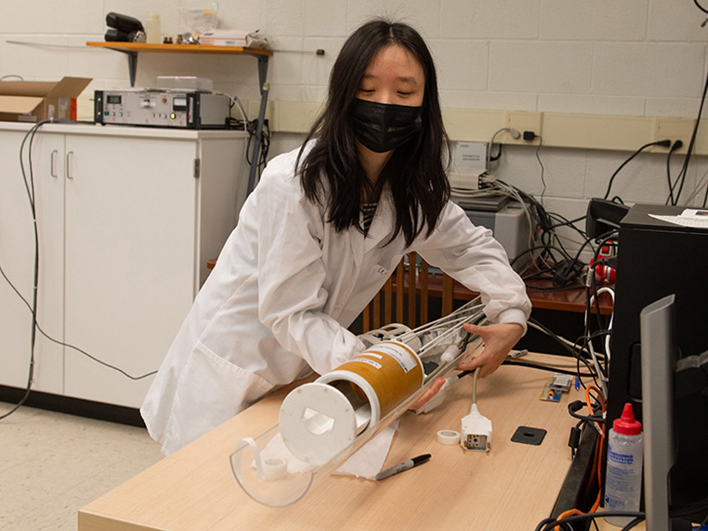 An individual in a lab coat adjusts a functional MRI machine. 