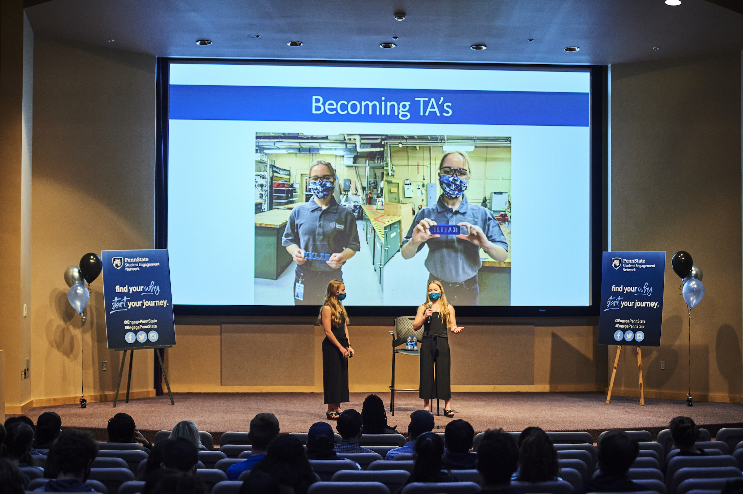 Two students present on a stage to audience