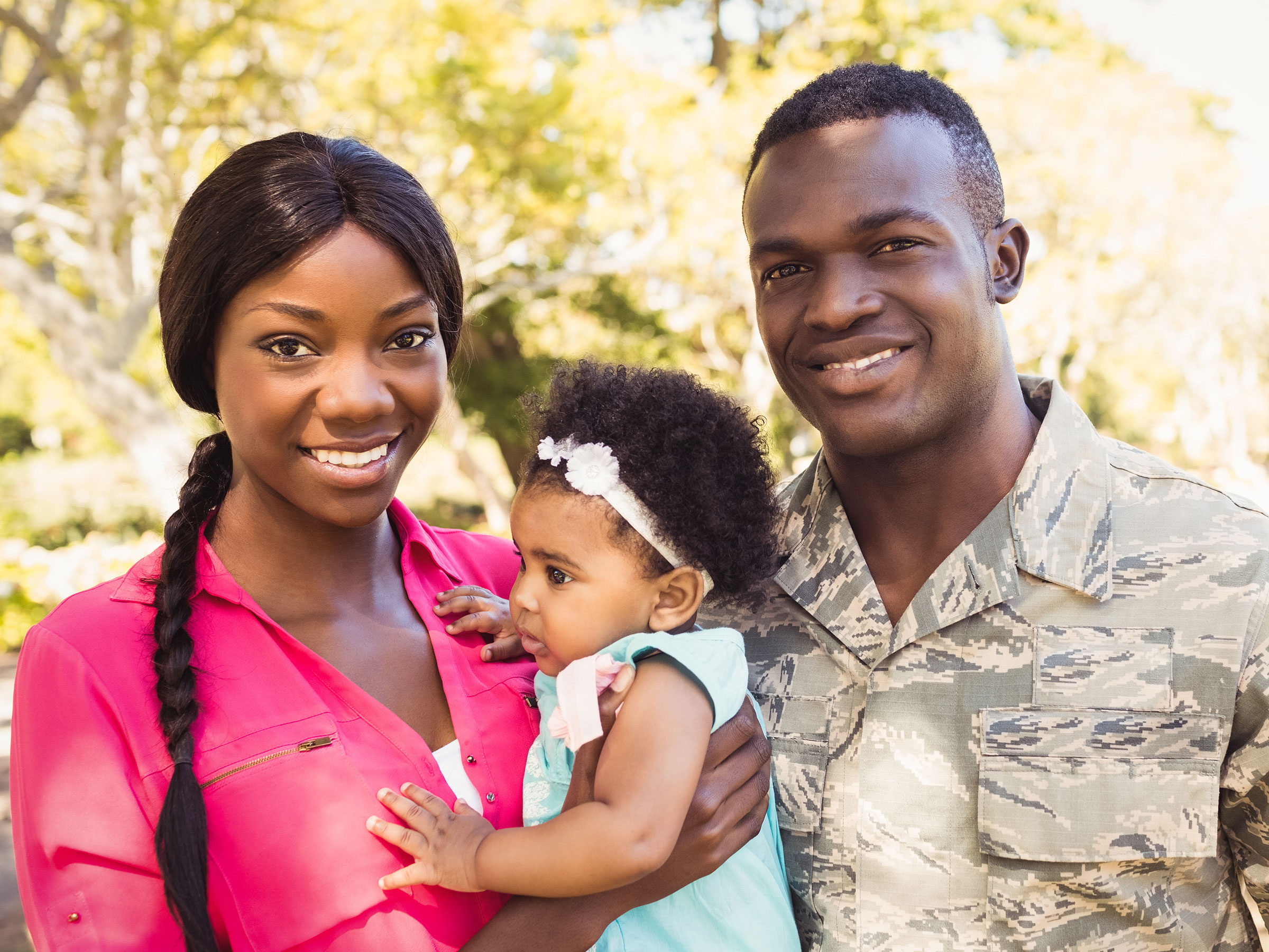 smiling father and mother holding baby, father is wearing military uniform