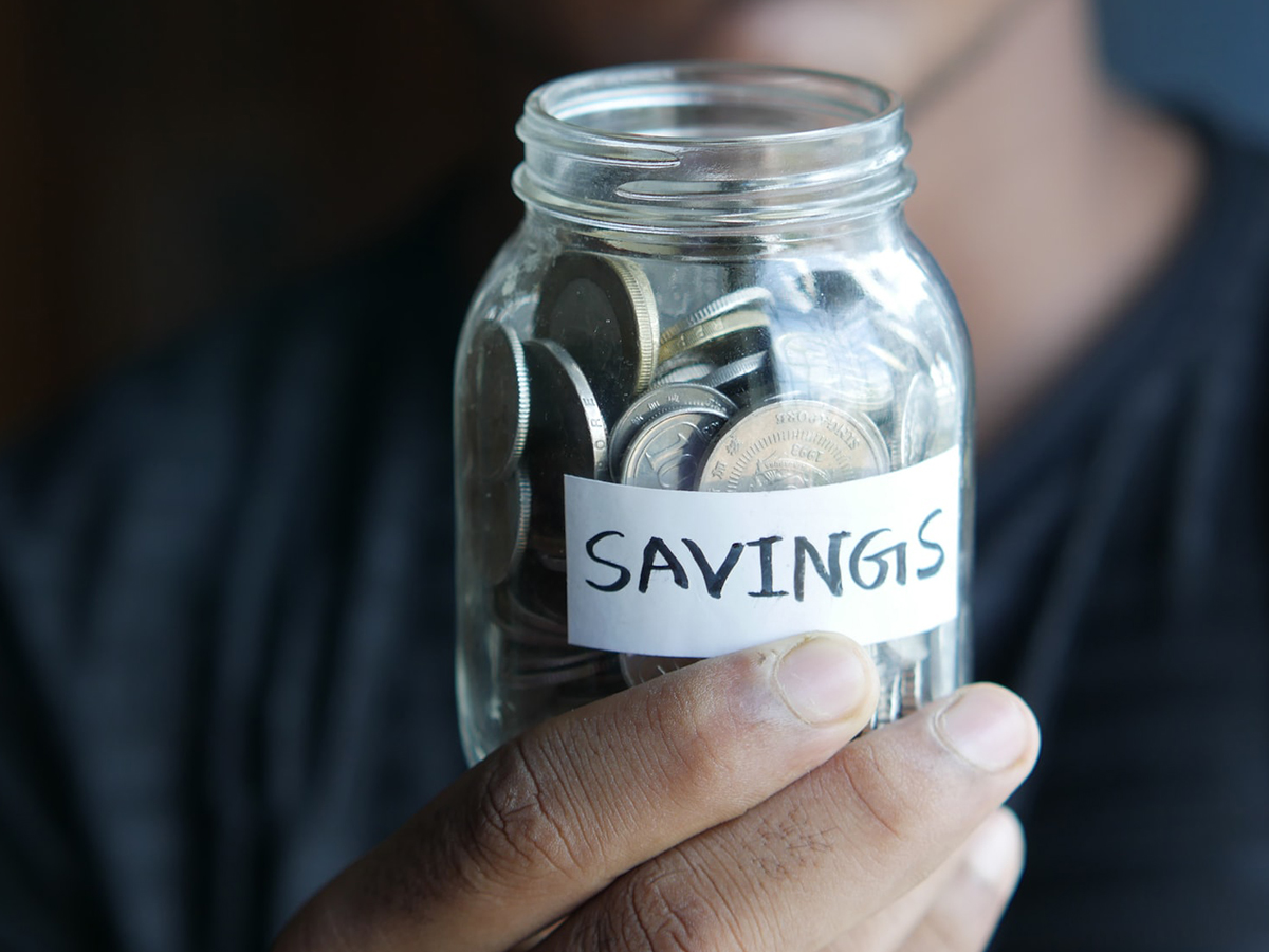 A photo of coins in a jar labeled savings.