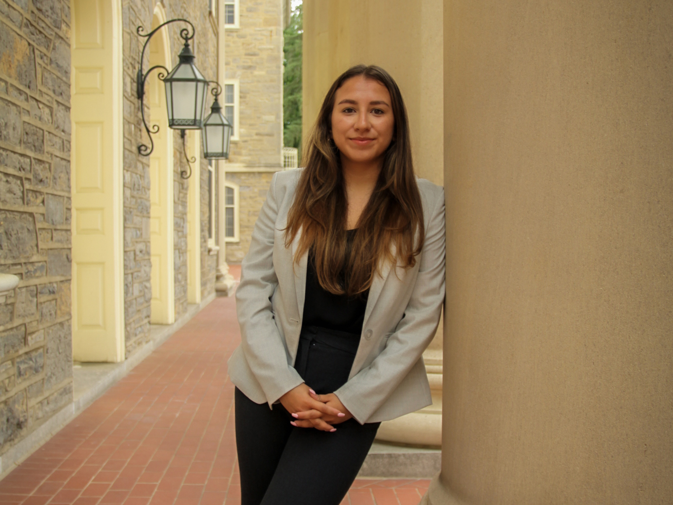 Samantha Escobar, a third-year Liberal Arts student at Penn State, leans against a pillar outside the main entrance to Old Main.