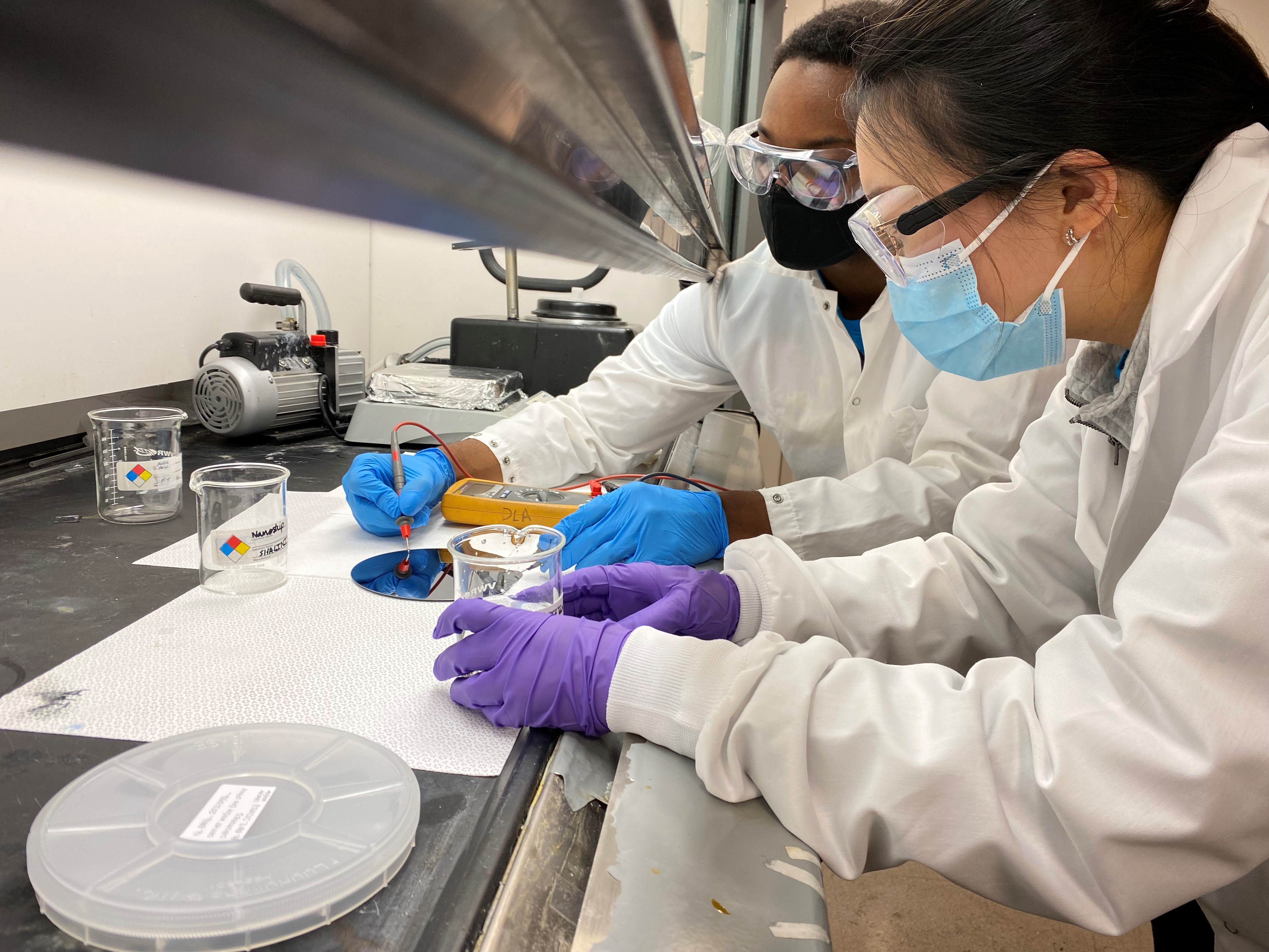 Two women working with lab equipment during experiment