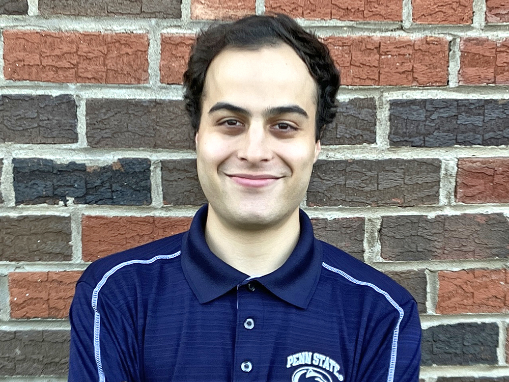 Taylor Rosen wearing a blue Penn State shirt standing in front of a brick wall