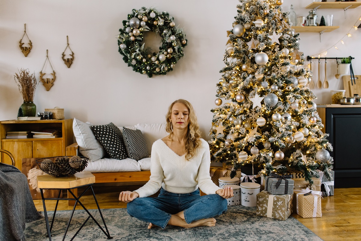 A woman meditates in a home decorated for the holidays.