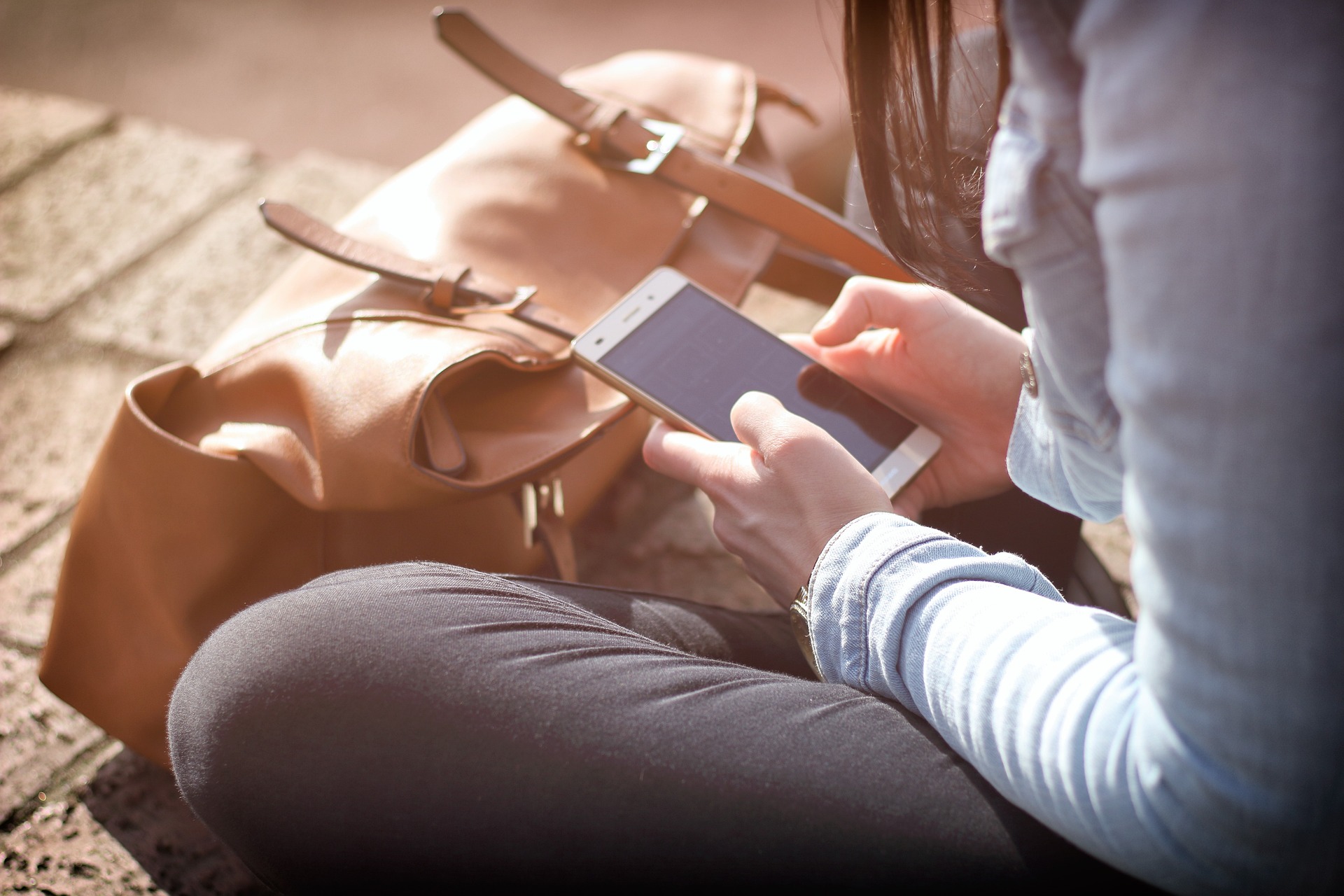 A woman sitting on the ground holding a smartphone