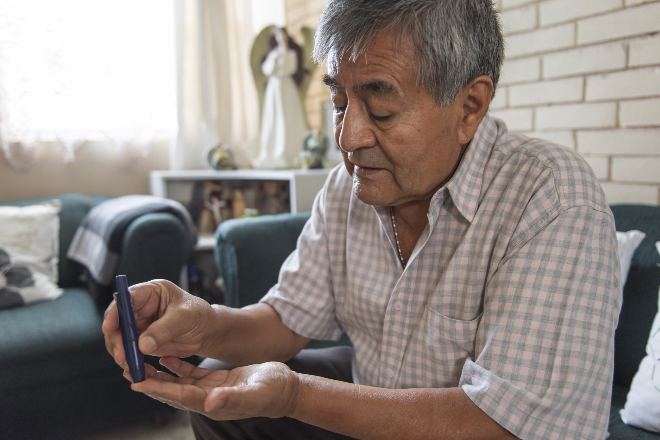 Older Hispanic man sticks his finger to test his blood sugar