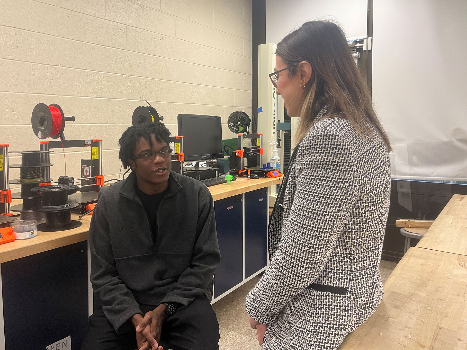 A student and a teacher talk together in a lab.