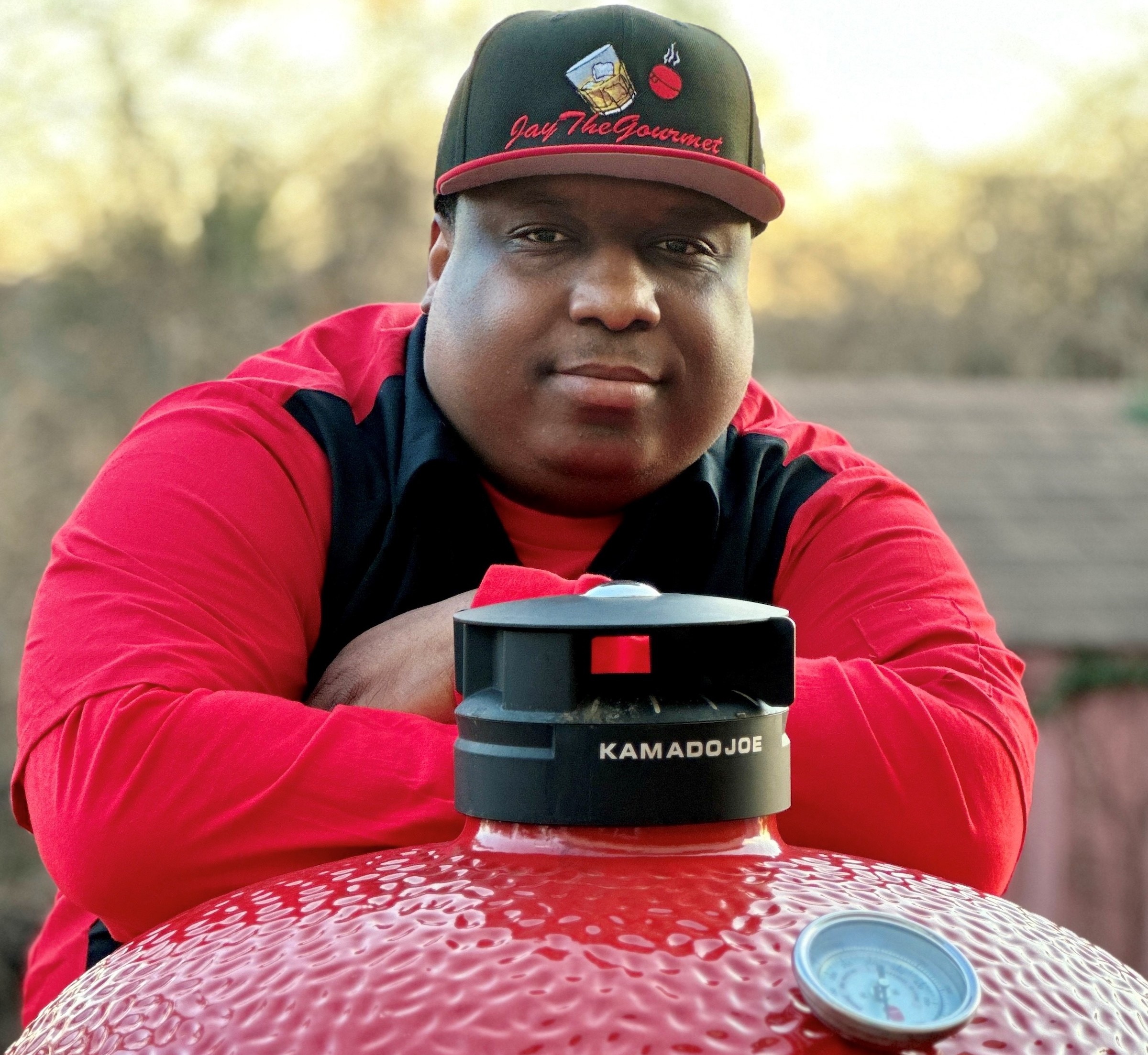 Photo of Joel Gill Jr. posing with a red and black grill