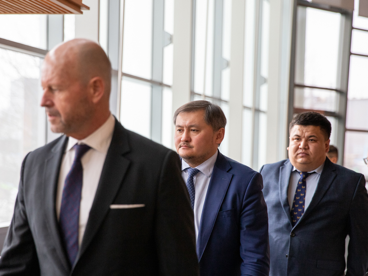 three men walk through a well-lit library