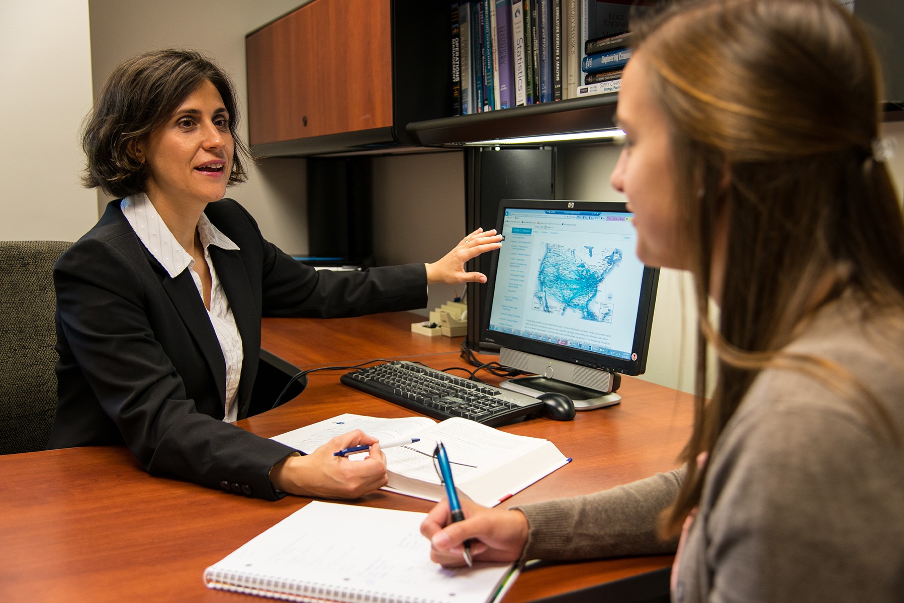 A Penn State Behrend professor talks with a student while pointing to a computer monitor.