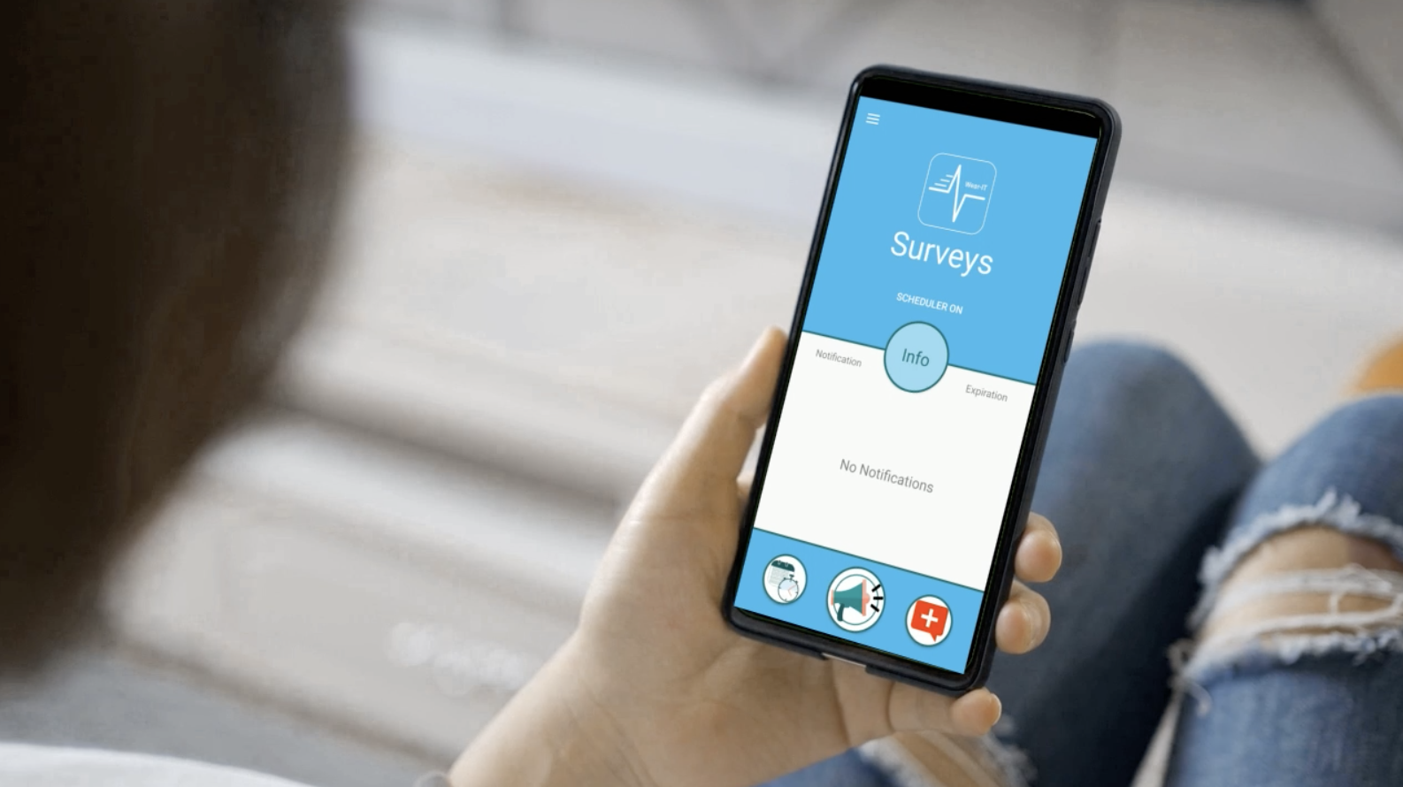 Woman holding a smart phone in her hand, showing a survey screen from the WearIT app