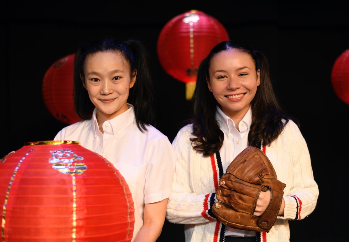 Two girls of Chinese nationality wear pigtails and hold a lantern and a baseball glove.