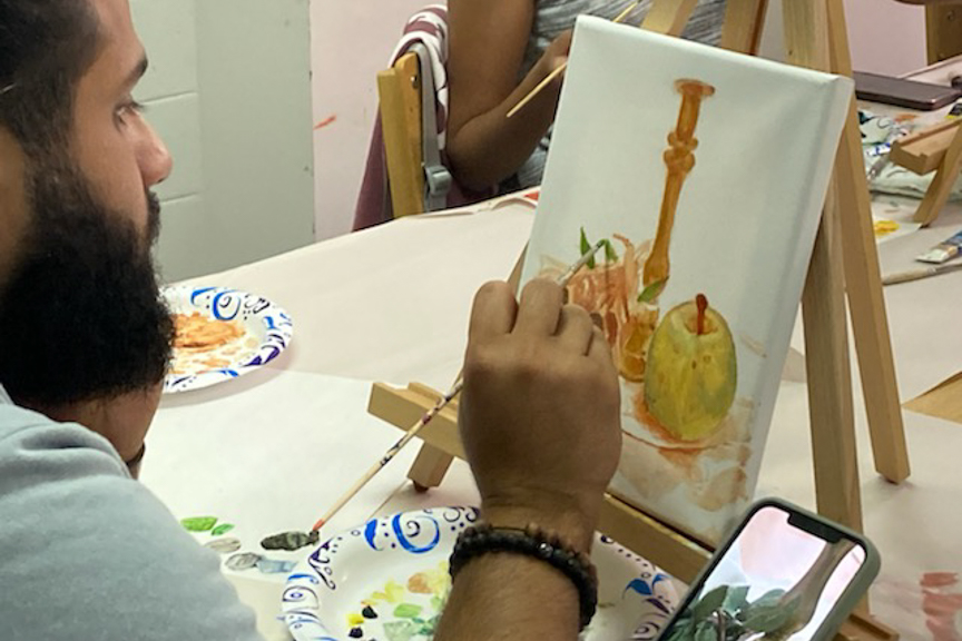 Center for Arts and Crafts workshop attendee painting on a canvas.