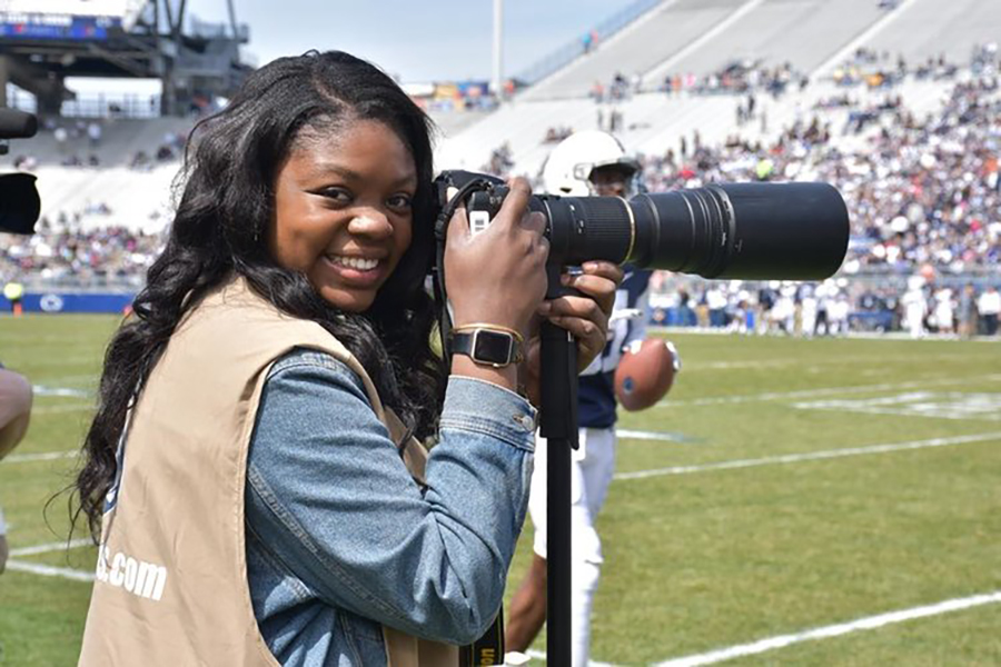 Adriana Lacy holding a camera while on the sideline at a football game