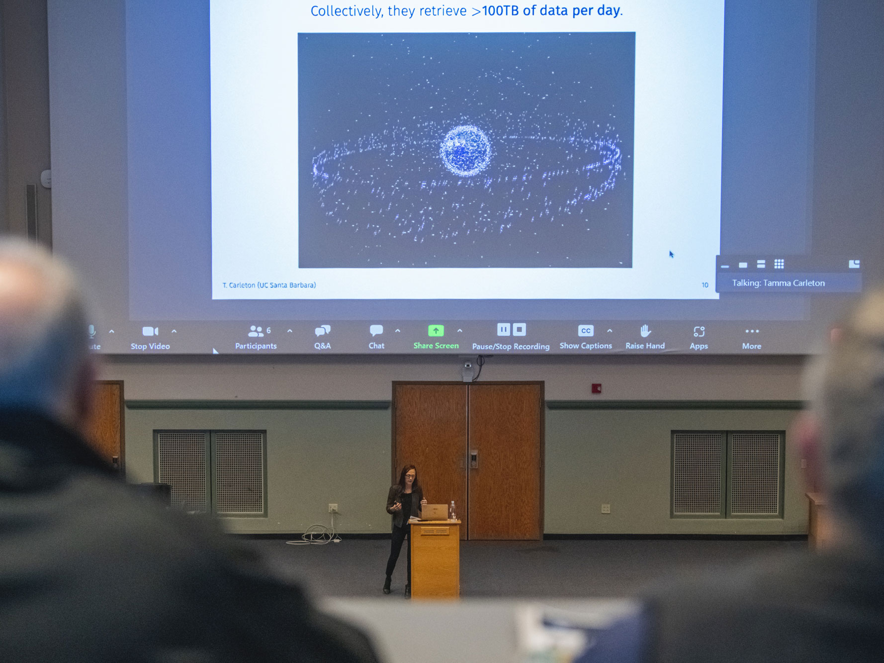 Tamma Carleton speaks at podium with projection of data on above screen