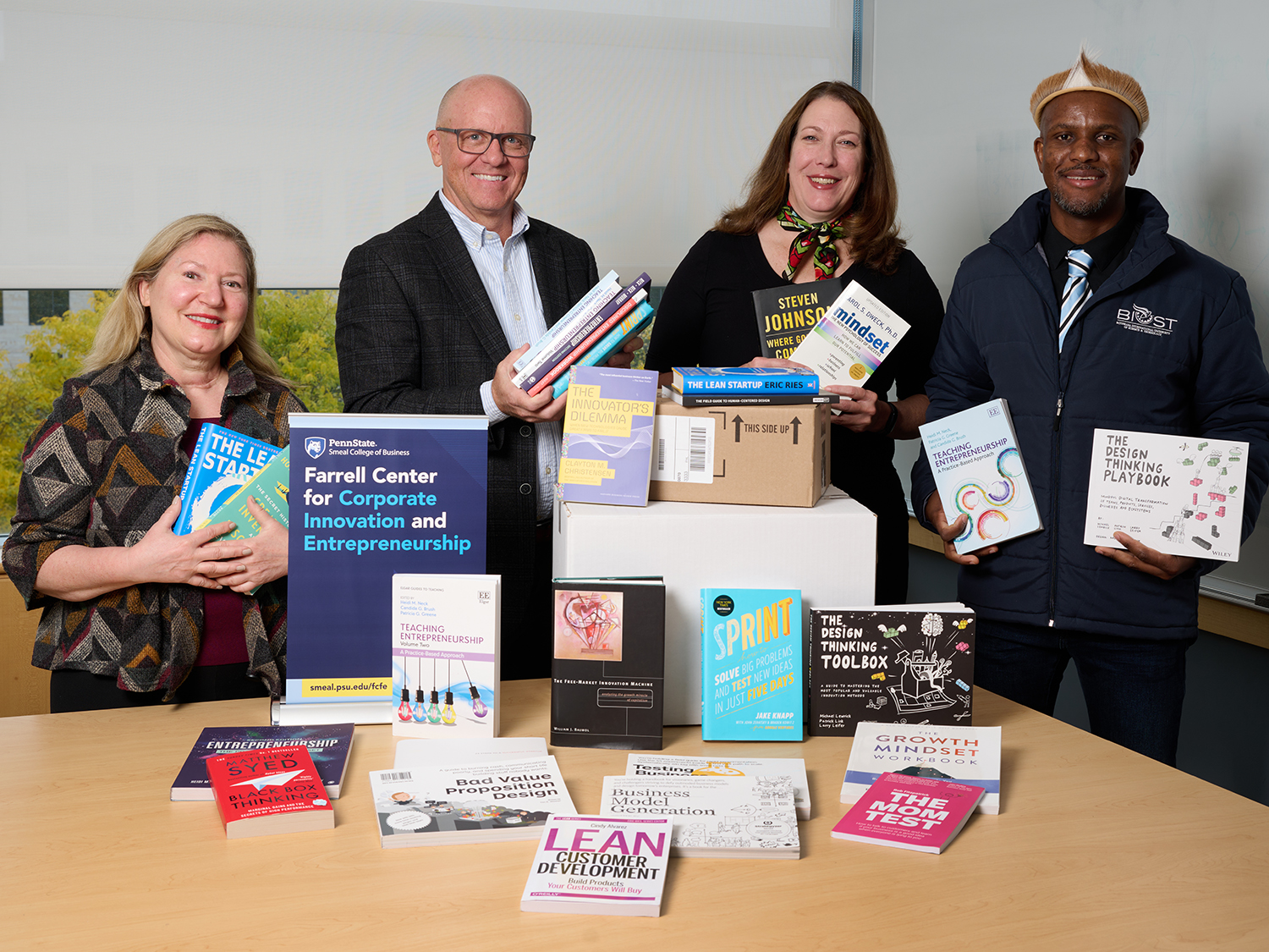 A photo of four people standing behind a table with books on display.