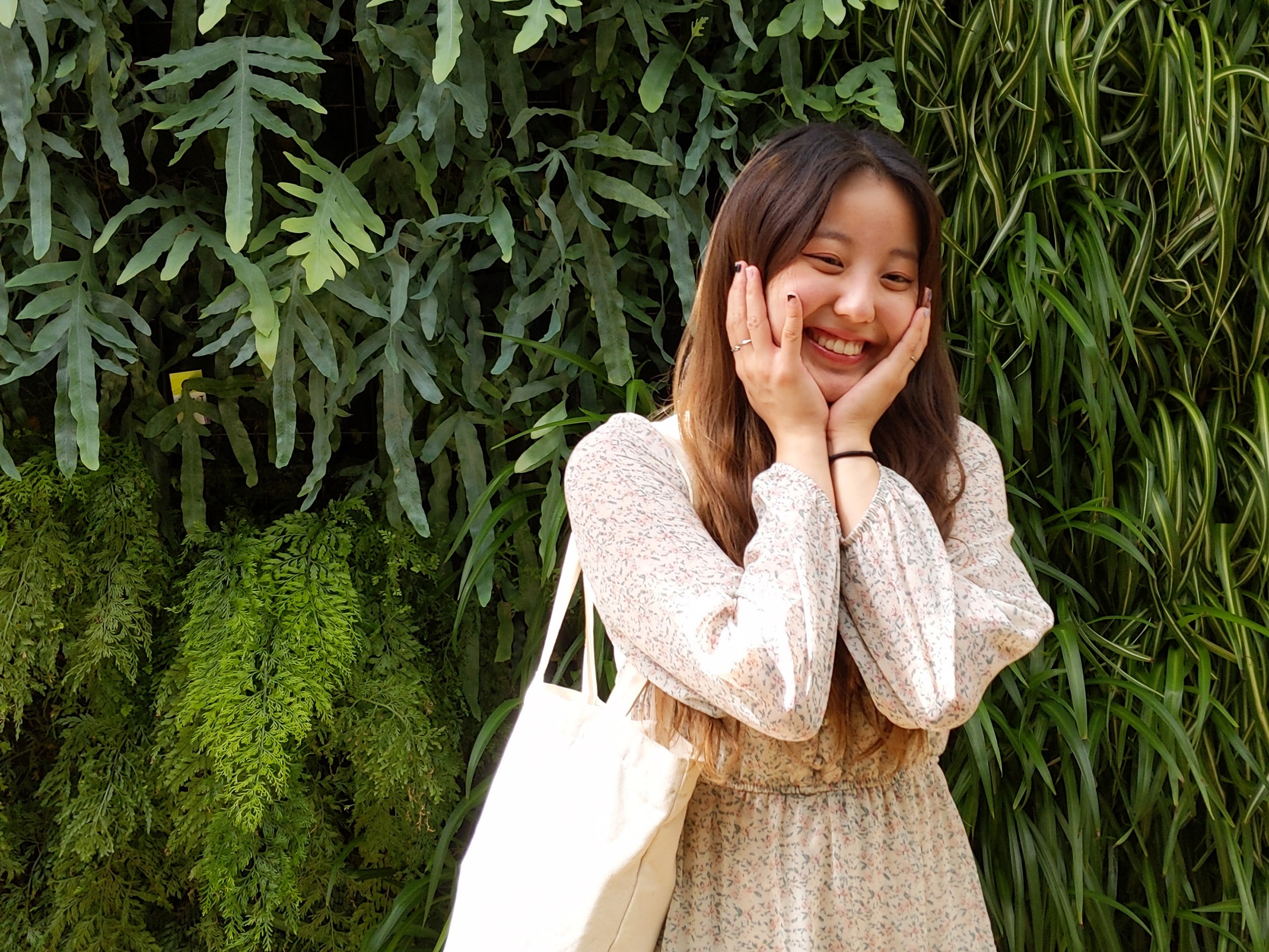 Cindy Choe stands in front of a plant wall.