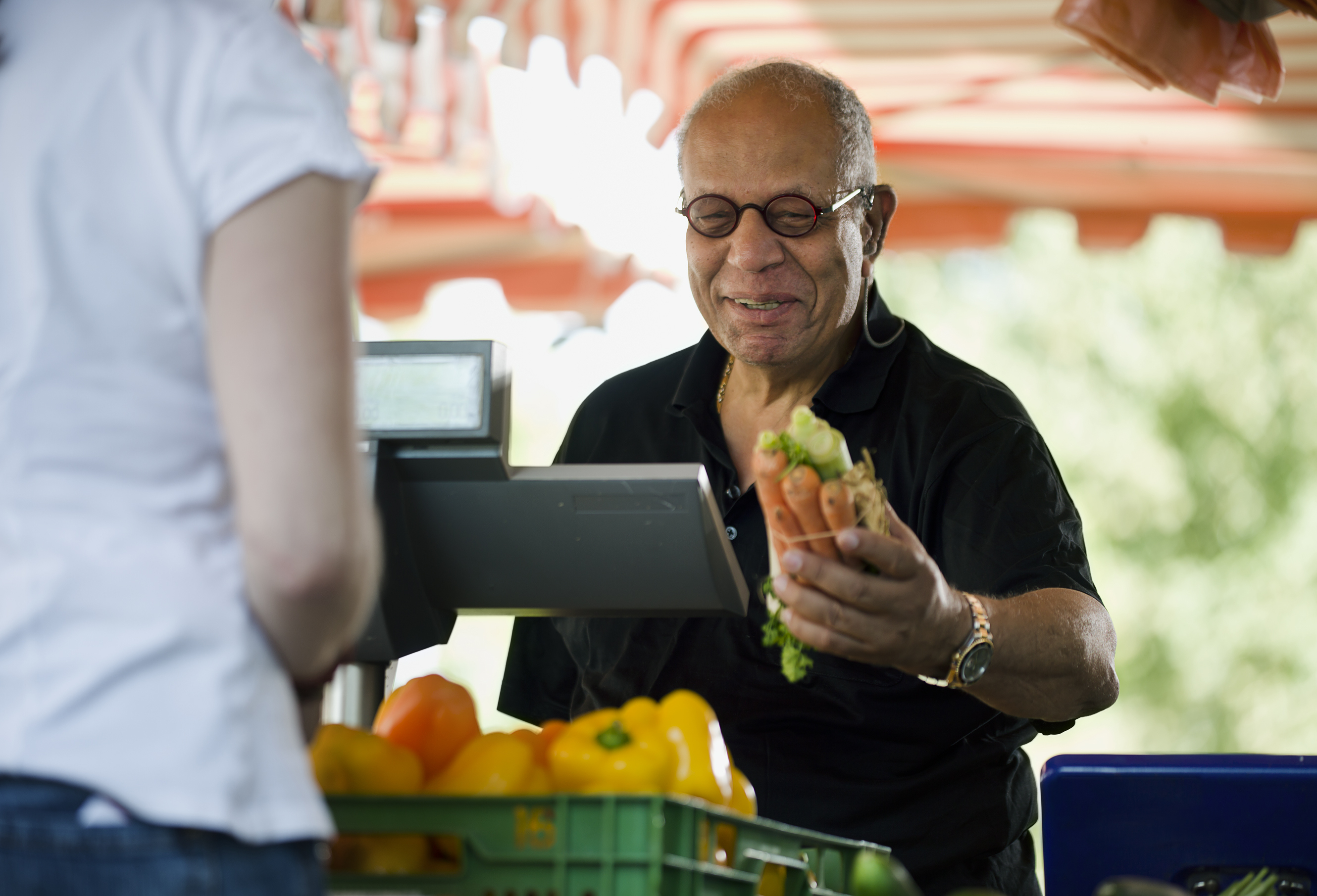 Older man buying carrots at a farmers market 